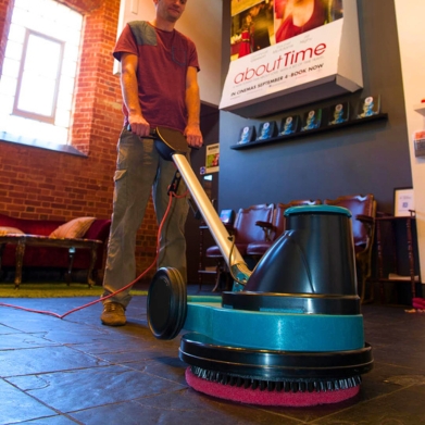 Man pushing floor buffer in café